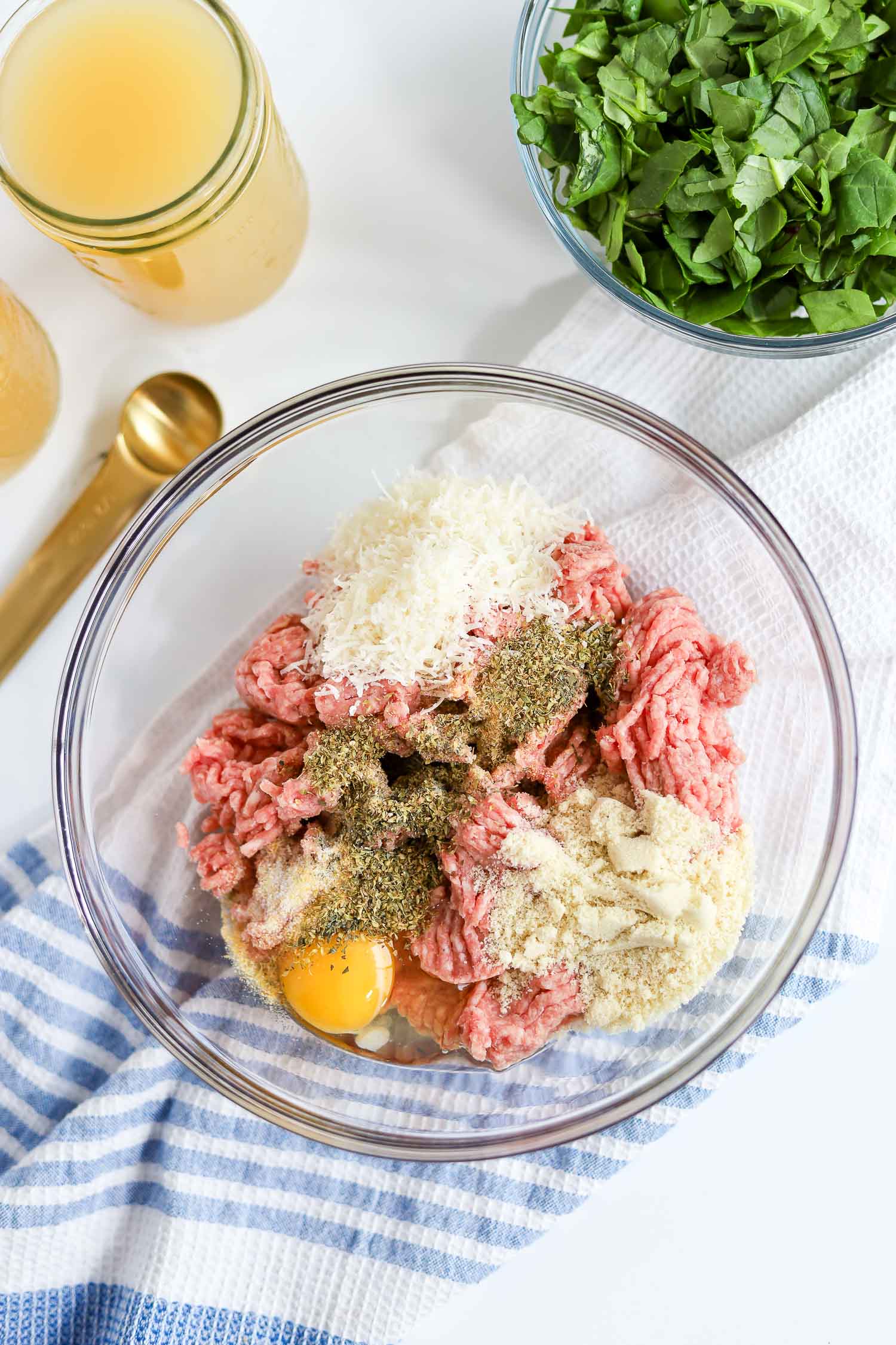 adding meatball ingredients in a glass bowl